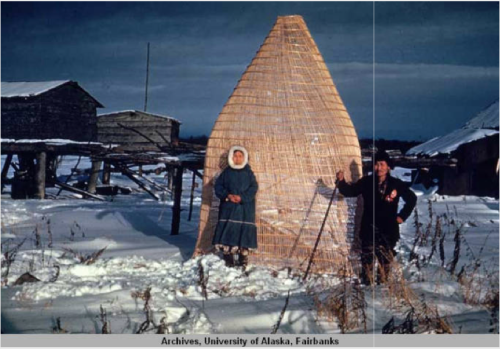 Title from caption. Handwritten note reads "Kwithluk fish trap [Kwethluk]." Alaska Native man and woman pose in front of a structure identified as a fish trap. Kwethluk, SW Alaska. Source: http://vilda.alaska.edu/cdm/singleitem/collection/cdmg11/id/12049/rec/25