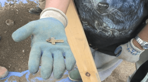 Cross found at the disturbed burial site.  Screenshot from Vimeo.